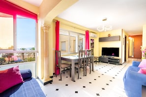 Una sala de estar con una mesa de comedor, sillas, un sofá, un televisor y una chimenea.