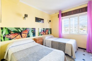 Habitación de hotel con dos camas, ventana con vistas y decoración de mariposas en la pared.