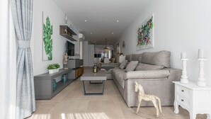 Een moderne woonkamer met een grijze bank, een witte bijzettafel en een decoratieve beeldje van een hond.