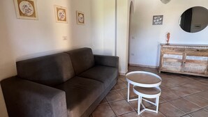 Uma sala de estar com sofá, mesa redonda pequena e um armário.