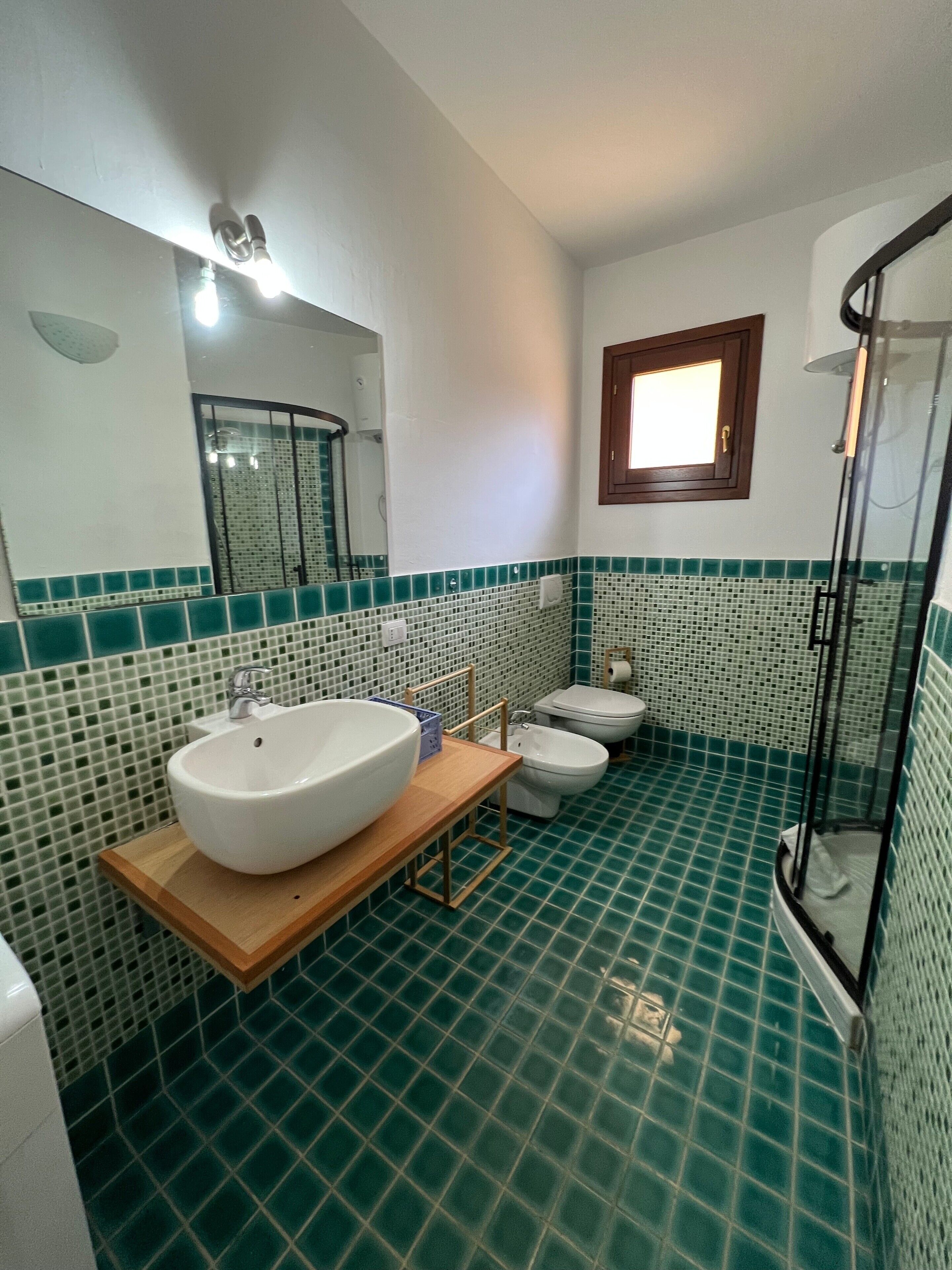 Une salle de bain comprenant un grand lavabo, des toilettes, un bidet et un espace douche.
