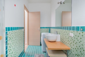 A bathroom with a sink, mirror, and tiled walls. - Apartment 'Orizzonti 31' with Sea View, Private Terrace and Air Conditioning (Golfo Aranci)