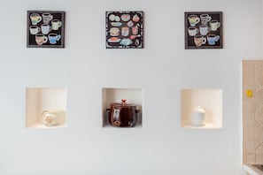 A wall with three framed illustrations of mugs and a shelf with a teapot and a salt shaker. - Apartment 'Orizzonti 31' with Sea View, Private Terrace and Air Conditioning (Golfo Aranci)