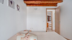 Une chambre à coucher avec un lit, un plafond en bois et une porte donnant sur une autre pièce.