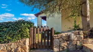 Un mur de pierre avec une porte en bois, un escalier en pierre et un bâtiment doté d’un balcon.