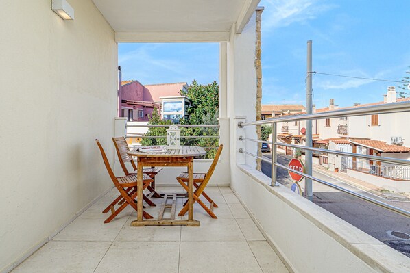 A balcony with a table and chairs, a stop sign, and a view of buildings.