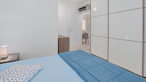 Un dormitorio con cama, mesita de noche, escritorio y armario.