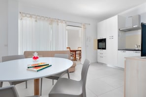 A modern kitchen with white cabinets, a black oven, and a wooden countertop.