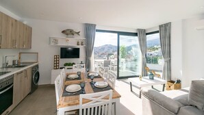 Ein modernes Apartment mit Essbereich, Küche und einem Balkon mit Blick auf die Stadt.