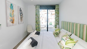Ein Hotelzimmer mit Bett, Sessel und Blick auf Gebäude, außerdem Kunstwerk an der Wand.