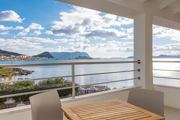 Un balcon offrant une vue sur un plan d’eau, une montagne et un paysage urbain.