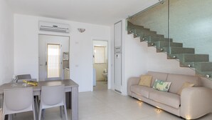 A modern living space with a dining area, a sofa, and a staircase.