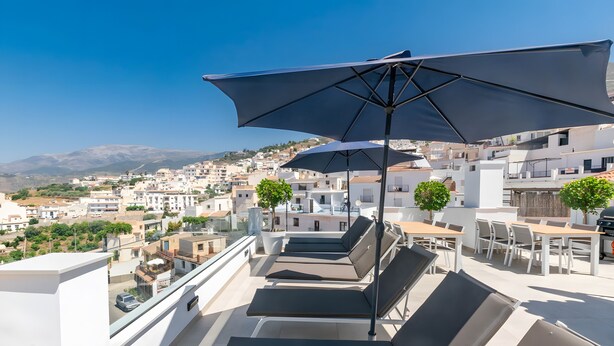 A rooftop terrace with sun loungers, umbrellas, and a view of a coastal town. - Luxury Apartment with shared swimming pool and jacuzi (Cómpeta)
