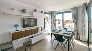 A modern dining area with a TV, wooden cabinet, and a table set for two. - Luxury Apartment with shared swimming pool and jacuzi (Cómpeta)