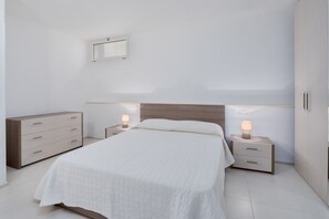 Ein Schlafzimmer mit einem Bett, zwei Nachttischen, einer Kommode und einer Wandleuchte.