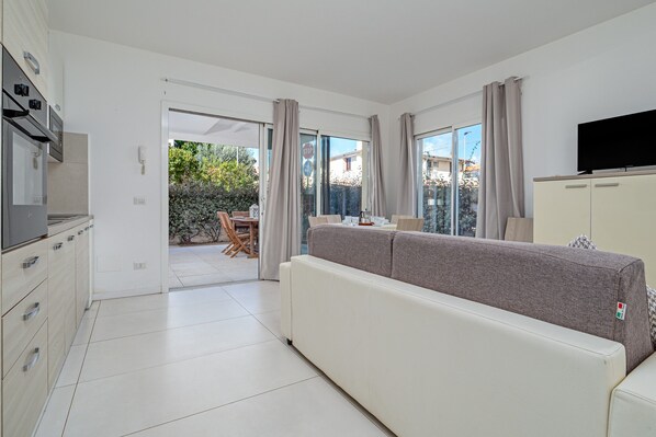 A modern living room with a sofa, TV, cabinets, and a dining area.