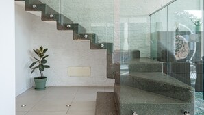 A modern staircase with glass railings, a potted plant, and a textured wall. - Villa "Cormorani 1" with Sea View, Jacuzzi & Wi-Fi (golfo aranci)