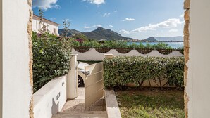 A narrow pathway leading to a building with a view of the sea and mountains. - Villa "Cormorani 1" with Sea View, Jacuzzi & Wi-Fi (golfo aranci)