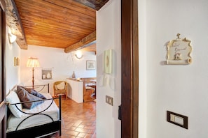 Una habitación con cama, una silla, una lámpara y techo de madera.
