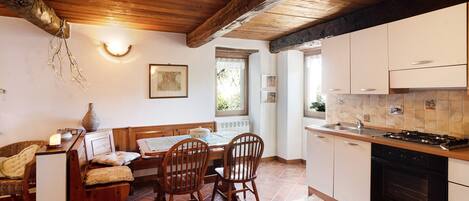 A kitchen with wooden cabinets, a stove, and a dining area with chairs and a table.