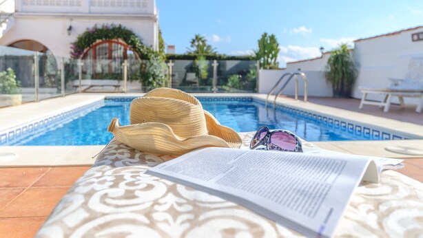 A poolside area with a patterned cushion, a hat, sunglasses, and a book. - Villa 'Jardin Tropical' with Private Pool, Garden A/C & Wi-Fi (Manilva)