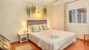 A bedroom with a bed, bedside tables, a window, and a view of the outside. - Villa 'Jardin Tropical' with Private Pool, Garden A/C & Wi-Fi (Manilva)