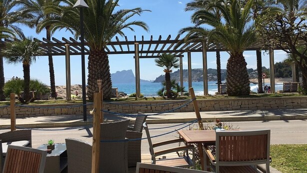 Una veranda sul mare con posti a sedere all'aperto, palme e vista sull'oceano.