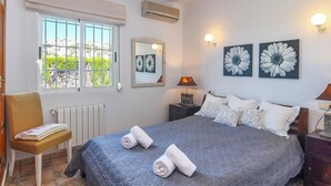 Una camera da letto con un letto, due lampade a parete, un termosifone, una finestra con persiane e una sedia.