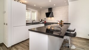Una cocina moderna con armarios blancos, una isla con encimera negra y un lavaplatos de acero inoxidable.