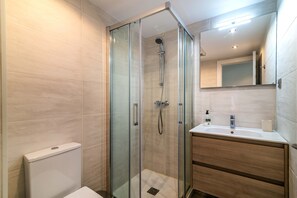 A modern bathroom with a glass-enclosed shower, a wooden vanity, and a large mirror. - Beautiful Apartment in Miraflores with Sea View, Shared Pool and Wi-Fi (Mijas Costa)
