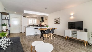 Un espacio habitable moderno con comedor, cocina y mueble de entretenimiento.