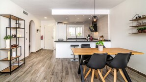 Una cocina moderna con una isla central, sillas negras y una mesa de comedor de madera.