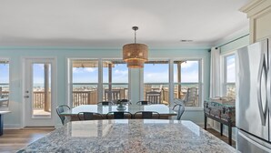 A kitchen with a granite countertop, stainless steel appliances, and a view of the beach. - Oceanfront 4BR, 2BA house on Oak Island, sleeps 10—perfect for family getaways! (Oak Island)