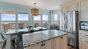 A kitchen with a large island, stainless steel appliances, and a view of the beach. - Oceanfront 4BR, 2BA house on Oak Island, sleeps 10—perfect for family getaways! (Oak Island)