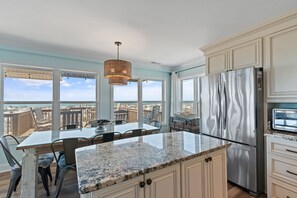 A kitchen with a large island, stainless steel appliances, and a view of the beach.