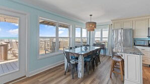 A kitchen with a large island, white cabinets, and a view of the beach. - Oceanfront 4BR, 2BA house on Oak Island, sleeps 10—perfect for family getaways! (Oak Island)