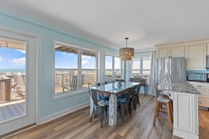 A kitchen with a large island, white cabinets, and a view of the beach.