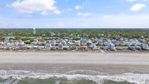 A coastal residential area with houses along the beach, a water tower, and a clear sky. - Oceanfront 4BR, 2BA house on Oak Island, sleeps 10—perfect for family getaways! (Oak Island)