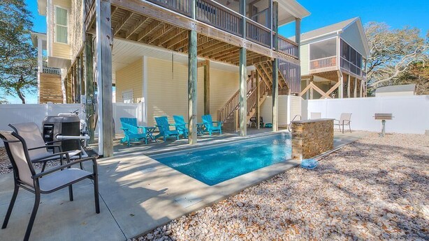 Ein zweistöckiges Haus mit Schwimmbad, Außenbereich zum Sitzen und einer überdachten Terrasse.
