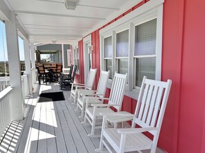 Un portico coperto con sedie in legno bianco e un tavolo da pranzo.
