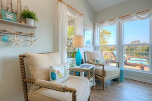 A cozy living room with a sofa, armchair, and a table with a lamp and decorative items.