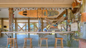 Eine Strandbar mit Surfbrett, Holzstühlen und rustikalem Interieur.
