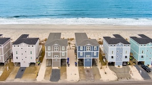 Ein Strandhotel mit mehrstöckigen Gebäuden, einem Sandstrand davor und dem Meer im Hintergrund.