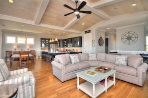 A spacious living area with a large sectional sofa, a dining table, and a kitchen in the background. - A Perfect Getaway: Private Pool, Elevator, Walk to Beach (Oak Island)