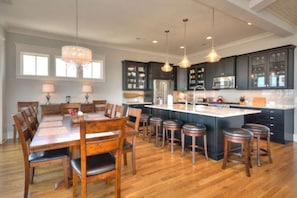 A spacious kitchen with a large island, dark cabinetry, and pendant lighting. - A Perfect Getaway: Private Pool, Elevator, Walk to Beach (Oak Island)