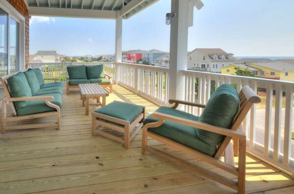 A covered outdoor seating area with wooden furniture and a view of the surrounding neighborhood. - A Perfect Getaway: Private Pool, Elevator, Walk to Beach (Oak Island)