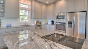 A modern kitchen with granite countertops, stainless steel appliances, and light-colored cabinetry. - Oceanview retreat in Oak Island with 4 bedrooms, perfect for family gatherings. (Oak Island)
