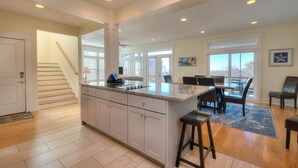 A spacious kitchen with a central island, a dining area with chairs, and a staircase leading to another level. - Oceanview retreat in Oak Island with 4 bedrooms, perfect for family gatherings. (Oak Island)