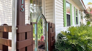 A house with a number '115' on the door, a green door, and a white exterior.