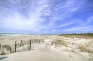 A sandy beach with a wooden fence and dunes. - Experience coastal charm at A Seaweed Shack, a spacious 3BR condo in Caswell Beach. (Caswell Beach)